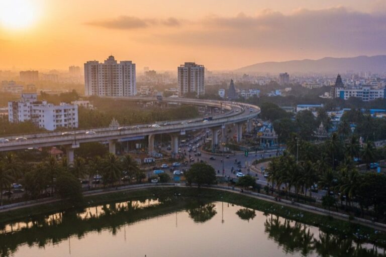 Wide city view of Porur in Chennai featuring the Porur flyover, nearby lake, surrounding residential buildings and evening skyline.