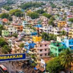 Aerial view of Arumbakkam in Chennai showing densely packed colorful houses, palm trees, busy roads, and urban residential buildings.