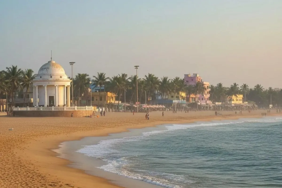 Besant Nagar (Elliot’s Beach) in Chennai with sandy shore, gentle waves, palm trees, and Karl Schmidt Memorial at sunrise